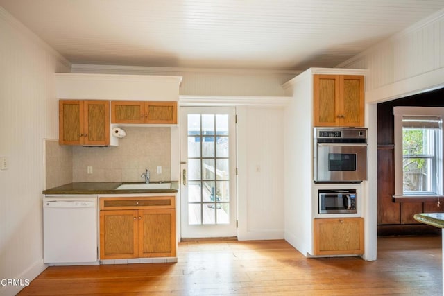 kitchen with sink, stainless steel appliances, backsplash, light wood-type flooring, and ornamental molding