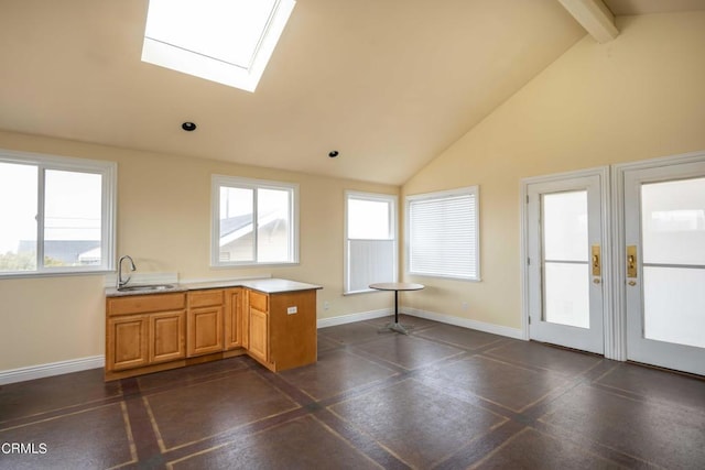 kitchen featuring beam ceiling, sink, high vaulted ceiling, and a skylight