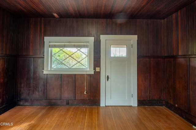 foyer with wood walls, wood-type flooring, a healthy amount of sunlight, and wooden ceiling