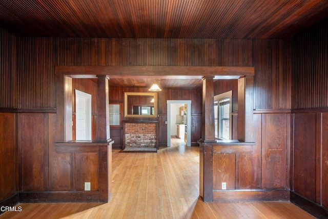 kitchen with wooden ceiling, decorative columns, wooden walls, and light hardwood / wood-style floors