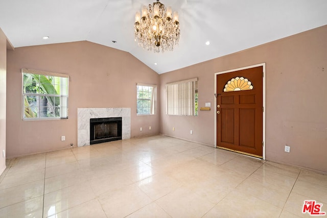 unfurnished living room featuring a notable chandelier, a high end fireplace, light tile patterned flooring, and lofted ceiling