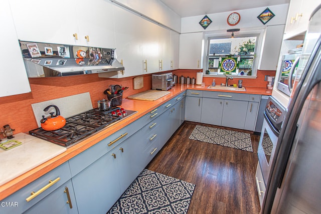 kitchen featuring extractor fan, sink, white cabinetry, stainless steel gas cooktop, and dark hardwood / wood-style flooring