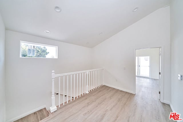 spare room with light hardwood / wood-style floors and vaulted ceiling