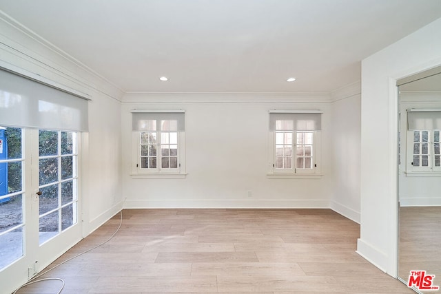 empty room with plenty of natural light, ornamental molding, and light hardwood / wood-style flooring