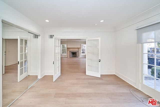 unfurnished room featuring light hardwood / wood-style floors, a tile fireplace, and french doors