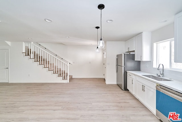 kitchen featuring white cabinetry, sink, appliances with stainless steel finishes, and light hardwood / wood-style flooring