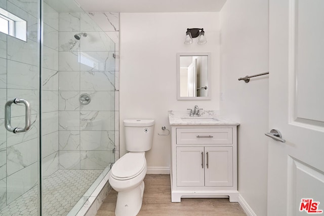 bathroom with wood-type flooring, vanity, toilet, and a shower with shower door