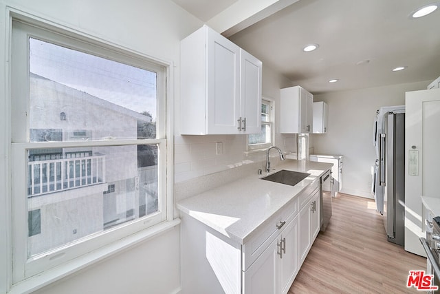 kitchen with sink, white cabinets, and light wood-type flooring