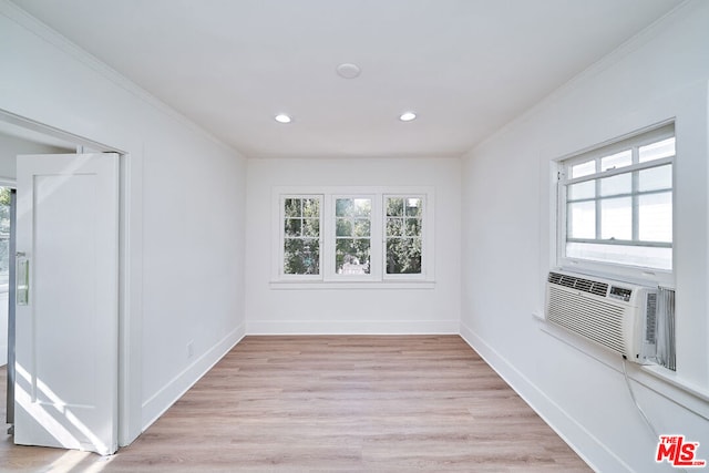 spare room featuring light hardwood / wood-style flooring, cooling unit, a healthy amount of sunlight, and crown molding