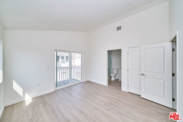 empty room featuring high vaulted ceiling and light hardwood / wood-style flooring