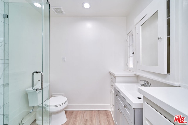 bathroom featuring walk in shower, toilet, vanity, and hardwood / wood-style flooring