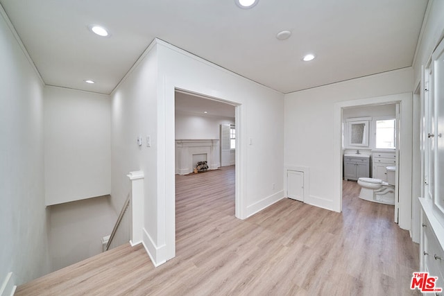 corridor featuring light hardwood / wood-style flooring, ornamental molding, and sink