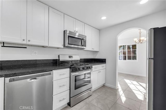 kitchen featuring white cabinetry, stainless steel appliances, light tile patterned floors, and an inviting chandelier