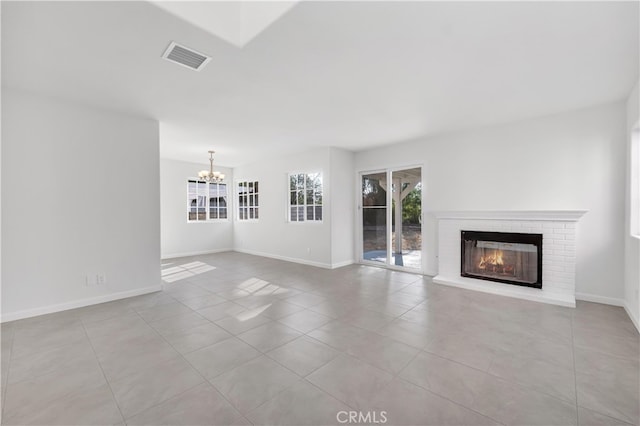 unfurnished living room featuring a chandelier, light tile patterned floors, and a brick fireplace