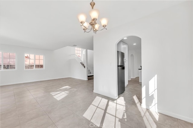 tiled empty room with an inviting chandelier