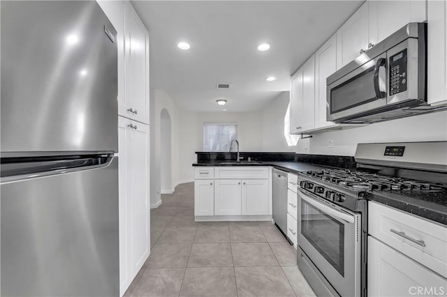 kitchen with white cabinets, appliances with stainless steel finishes, light tile patterned floors, and sink