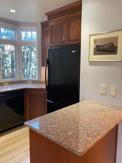 kitchen featuring light hardwood / wood-style floors, light stone counters, and black appliances