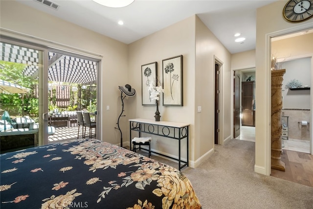 bedroom featuring ensuite bath, light colored carpet, and access to exterior