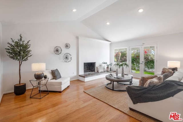 living room with light hardwood / wood-style floors, french doors, and vaulted ceiling