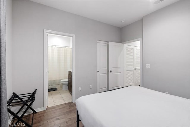 bedroom with ensuite bath, a closet, and light hardwood / wood-style flooring