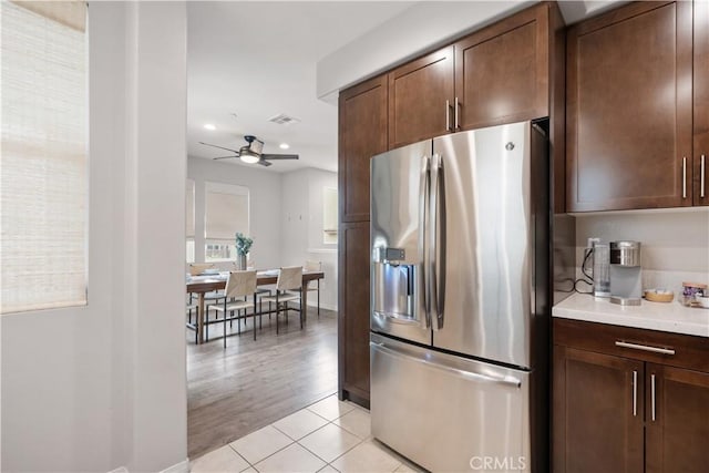 kitchen with light tile patterned flooring, ceiling fan, stainless steel refrigerator with ice dispenser, and dark brown cabinetry