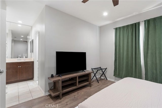 bedroom featuring sink, ensuite bath, ceiling fan, and light wood-type flooring