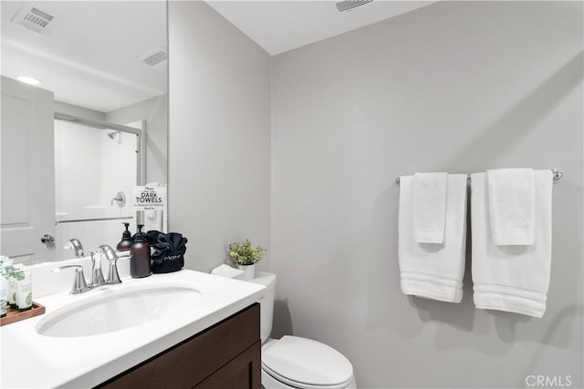 bathroom featuring toilet, a shower with door, and vanity