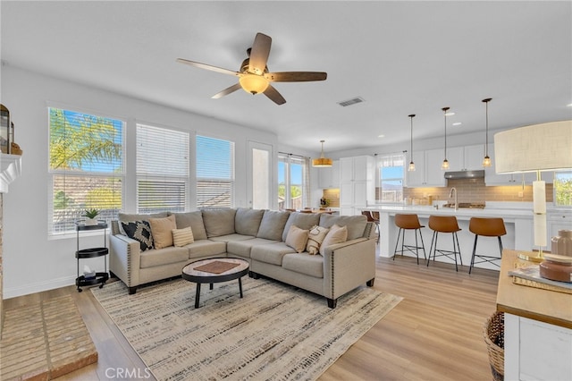 living room featuring ceiling fan, light hardwood / wood-style flooring, and sink