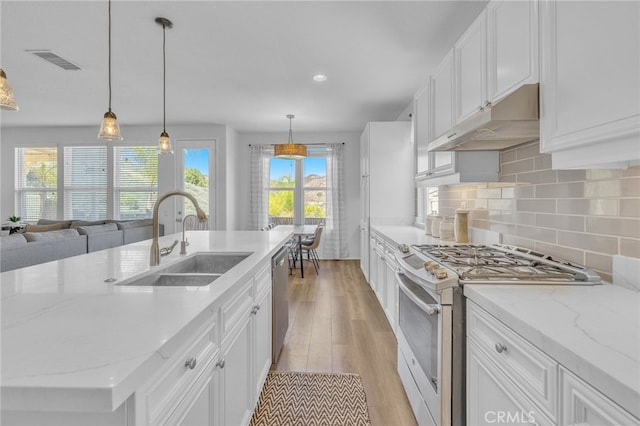 kitchen with sink, white cabinets, hanging light fixtures, light hardwood / wood-style flooring, and stainless steel appliances