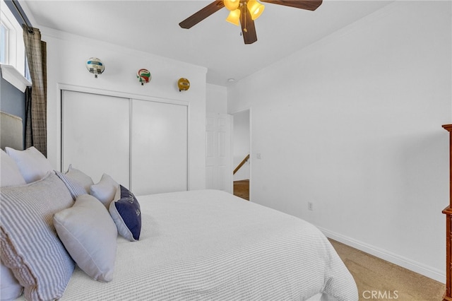 carpeted bedroom with ceiling fan and a closet