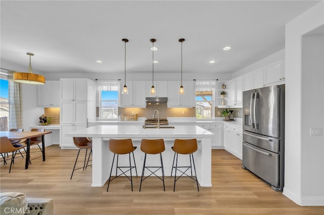 kitchen featuring white cabinets, plenty of natural light, and stainless steel fridge with ice dispenser