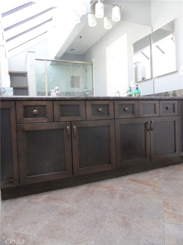 bathroom featuring walk in shower, vanity, and tile patterned flooring