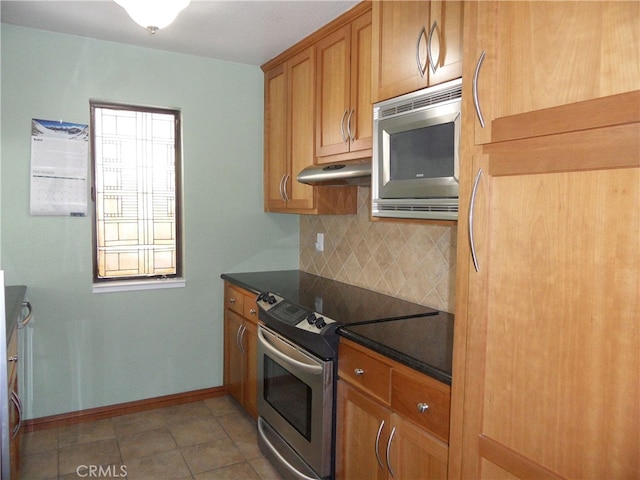 kitchen with appliances with stainless steel finishes, backsplash, and tile patterned flooring