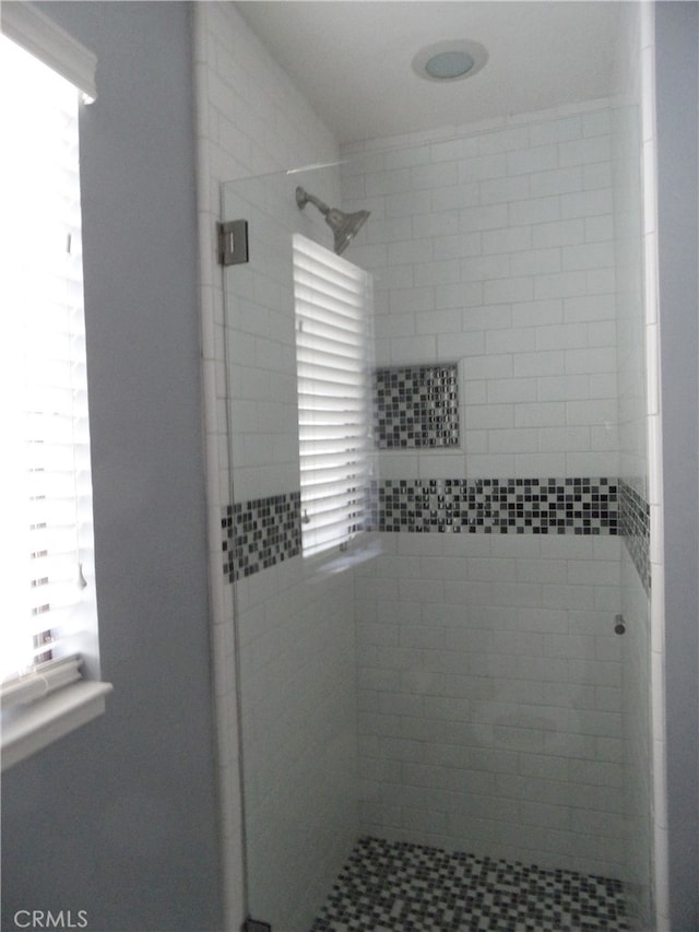 bathroom featuring a shower with door and a healthy amount of sunlight