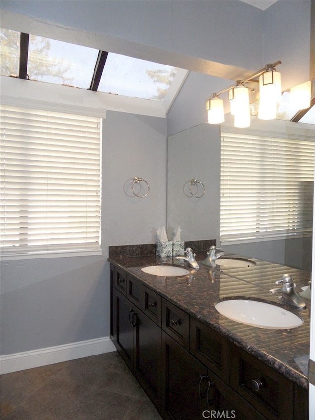 bathroom featuring lofted ceiling with skylight, vanity, and tile patterned floors