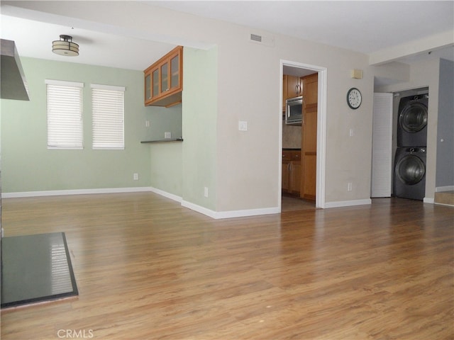 unfurnished living room with light hardwood / wood-style floors and stacked washing maching and dryer