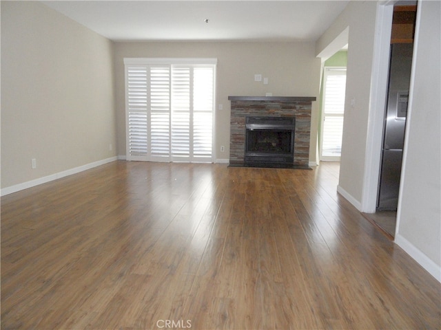 unfurnished living room with a wealth of natural light, a fireplace, and dark wood-type flooring