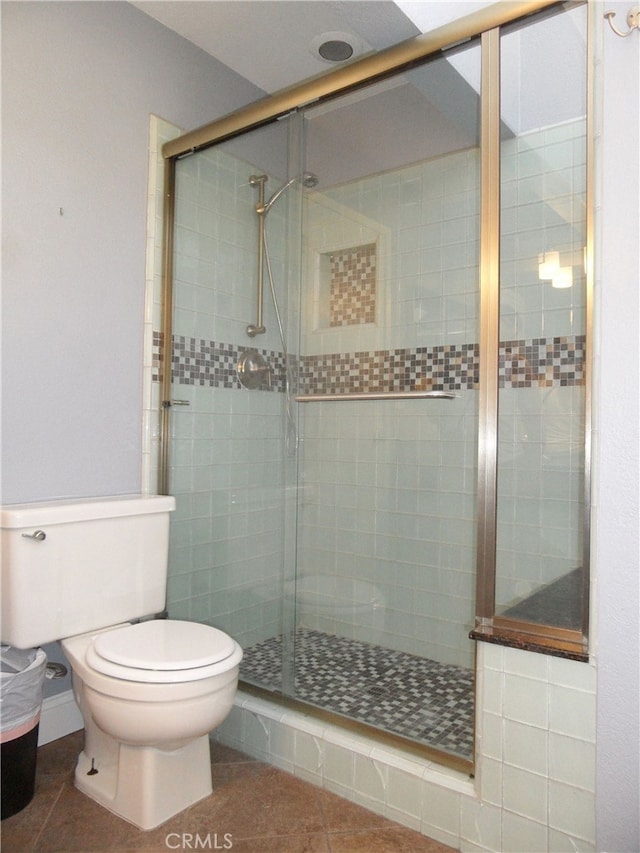 bathroom featuring tile patterned flooring, a shower with shower door, and toilet