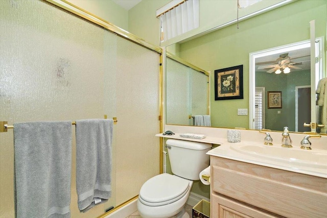 bathroom with ceiling fan, vanity, a shower with shower door, and toilet