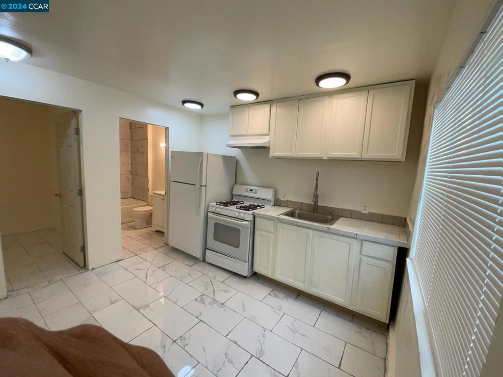 kitchen with white appliances, sink, and white cabinets