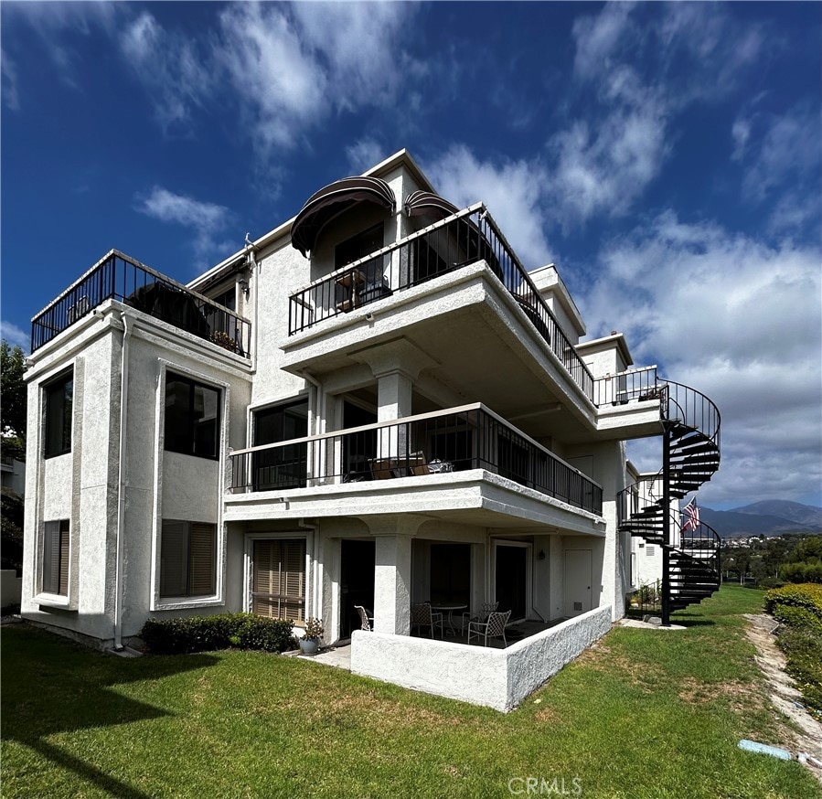 back of house featuring a balcony and a yard