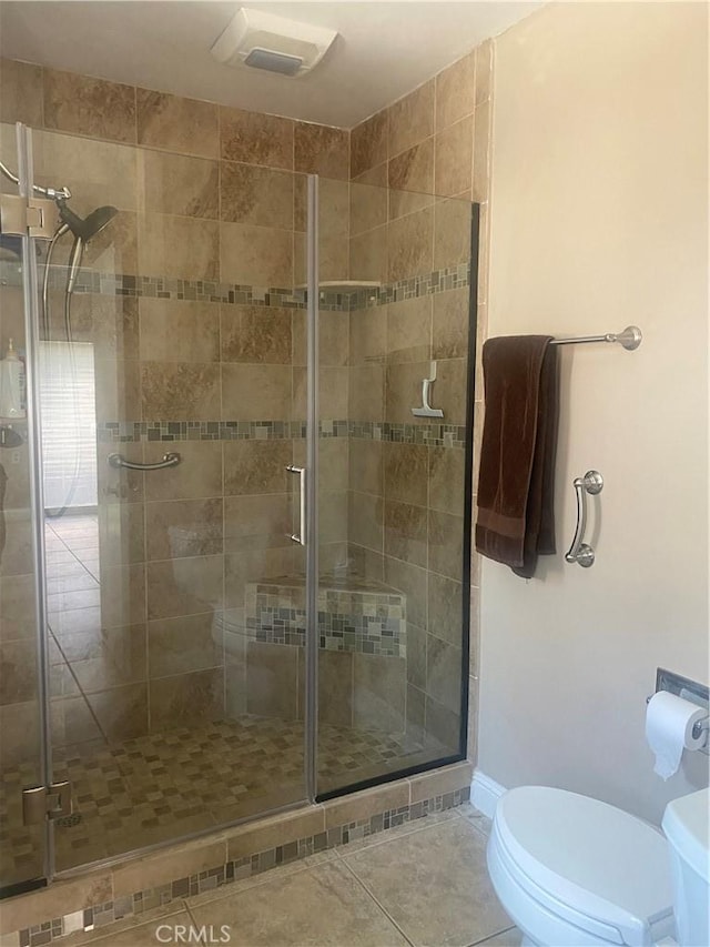 bathroom with tile patterned floors, toilet, and a shower with shower door