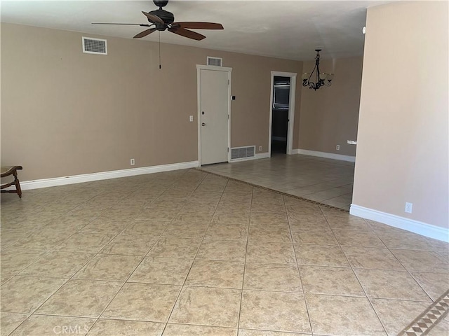 tiled spare room featuring ceiling fan with notable chandelier