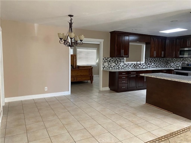 kitchen with decorative backsplash, appliances with stainless steel finishes, pendant lighting, and a notable chandelier