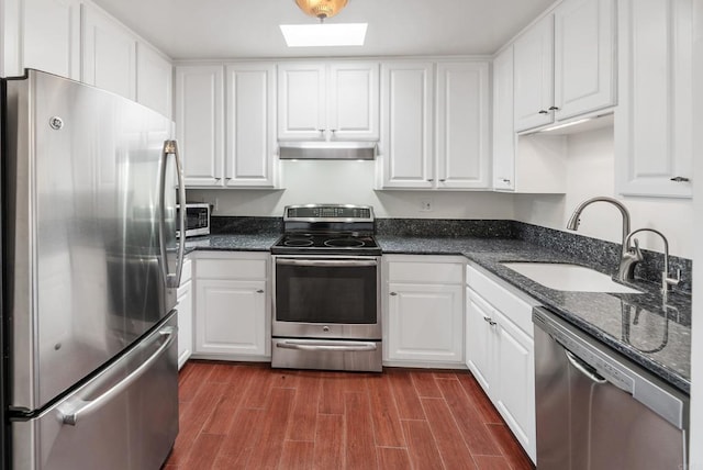 kitchen featuring dark wood-type flooring, sink, white cabinetry, stainless steel appliances, and dark stone countertops