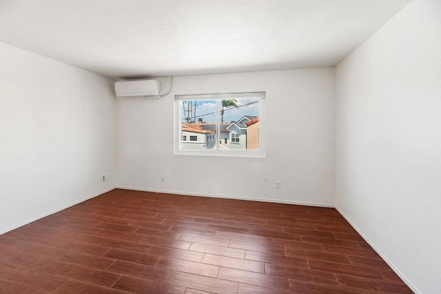 spare room featuring a wall unit AC and dark hardwood / wood-style floors