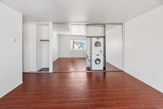 interior space with stacked washer / drying machine and dark hardwood / wood-style flooring