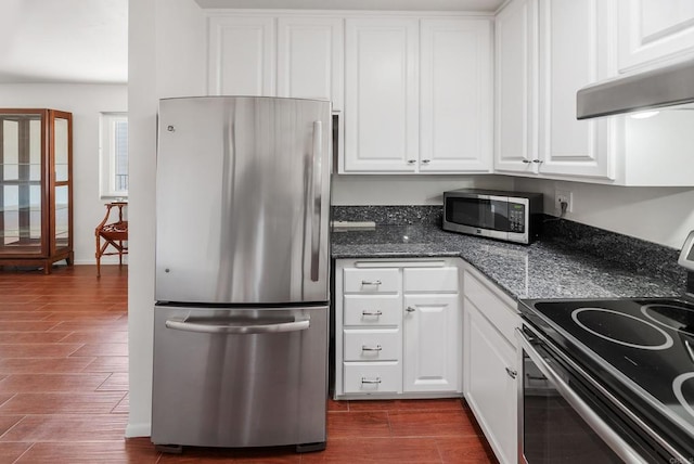 kitchen with dark hardwood / wood-style floors, range hood, white cabinetry, appliances with stainless steel finishes, and dark stone countertops