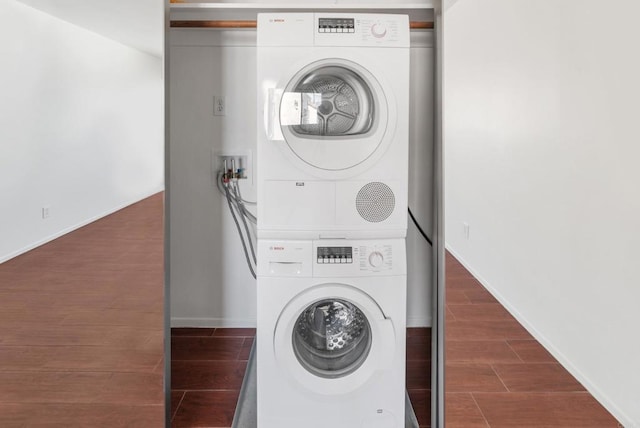 washroom with stacked washer and dryer and dark hardwood / wood-style flooring