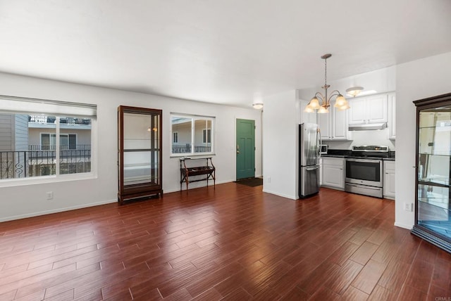 unfurnished living room featuring a notable chandelier and dark hardwood / wood-style flooring